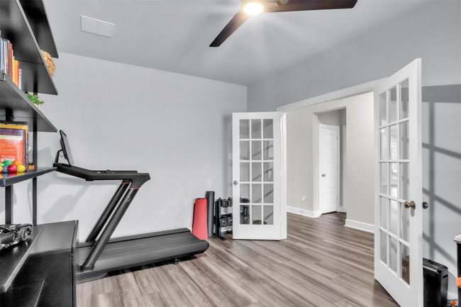 Workout area featuring visible vents, baseboards, french doors, wood finished floors, and a ceiling fan | Image 12