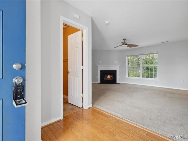 Unfurnished living room featuring a ceiling fan, a fireplace with flush hearth, and wood finished floors | Image 10