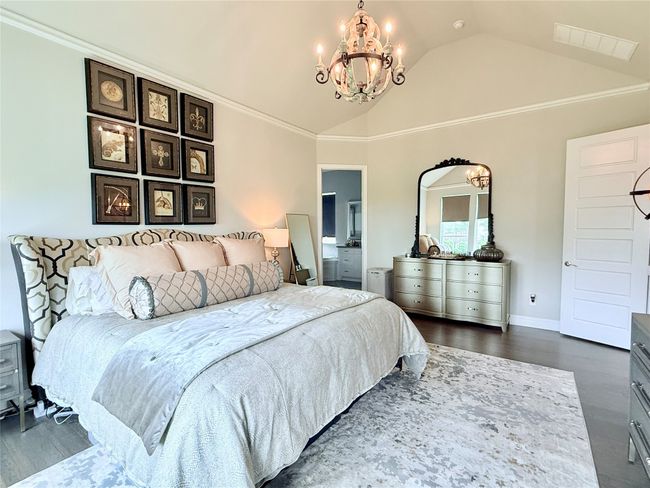 Bedroom featuring dark wood-type flooring, a chandelier, ensuite bath, crown molding, and high vaulted ceiling | Image 14
