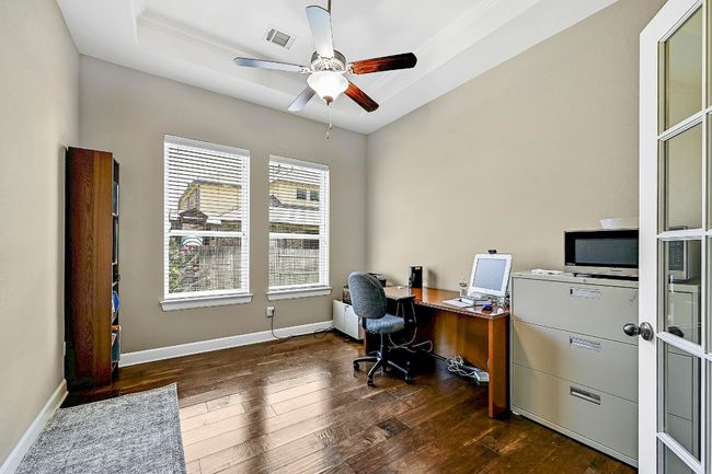 Office area featuring dark wood-style floors, a ceiling fan, and a tray ceiling | Image 14