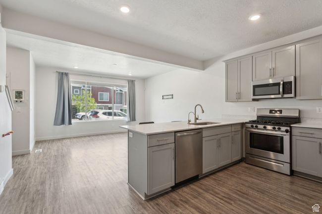 Kitchen featuring stainless steel appliances, LVP flooring, peninsula, with quartz countertops, and grey cabinetry | Image 11