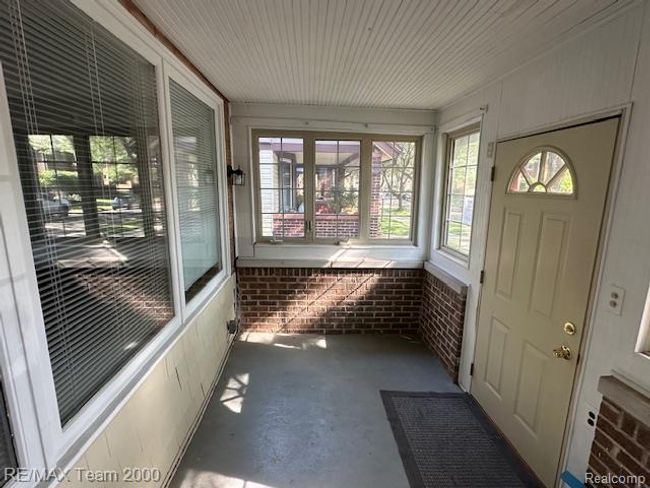 Unfurnished sunroom featuring unfinished concrete flooring and brick wall | Image 6
