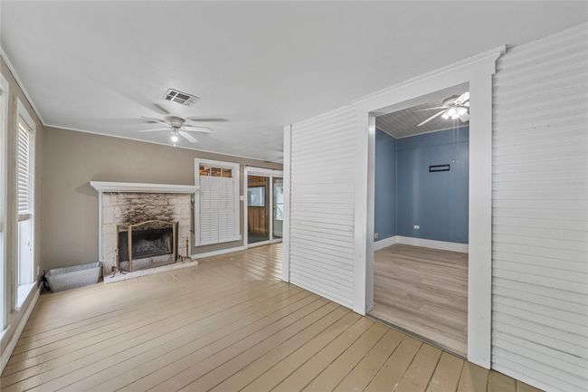Unfurnished living room featuring ceiling fan, hardwood / wood-style flooring, and a stone fireplace | Image 21