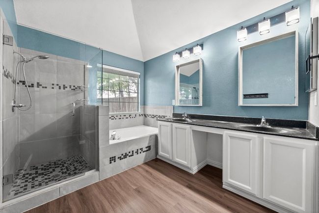 Bathroom with a bath, a shower stall, double vanity, wood finished floors, and lofted ceiling | Image 19