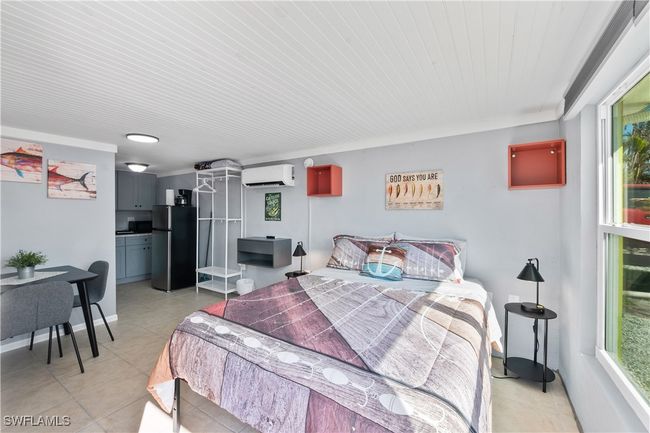 Bedroom featuring wood ceiling, a wall mounted AC, multiple windows, and stainless steel refrigerator | Image 16