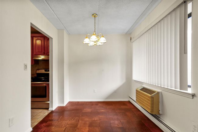 Unfurnished dining area with a baseboard heating unit, a chandelier, and a textured ceiling | Image 12