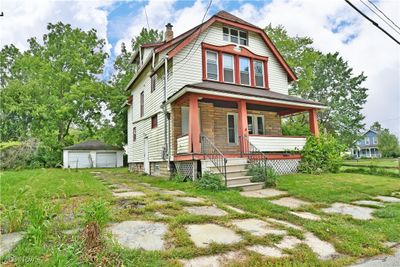 View of front facade featuring a garage, a front yard, an outdoor structure, and covered porch | Image 2