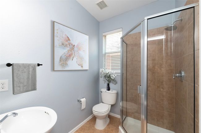 Full bath featuring tile patterned flooring, toilet, a sink, visible vents, and a stall shower | Image 7
