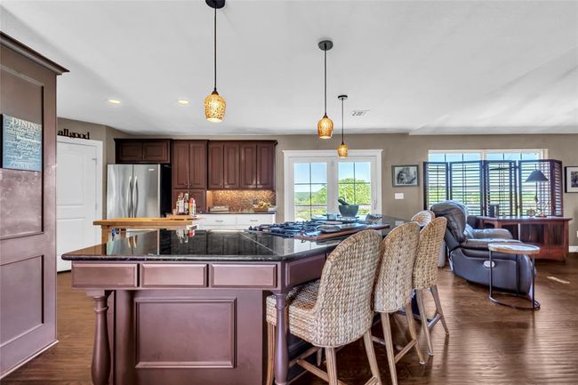 Kitchen featuring freestanding refrigerator, a center island, dark wood-type flooring, recessed lighting, and open floor plan | Image 10