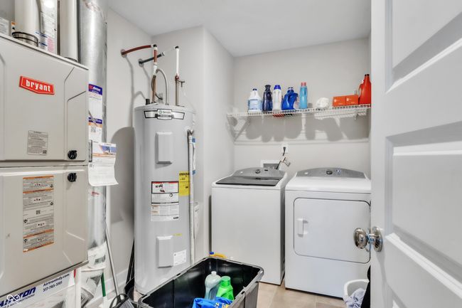 washroom featuring electric water heater, light tile patterned floors, washing machine and dryer, heating unit, and laundry area | Image 23