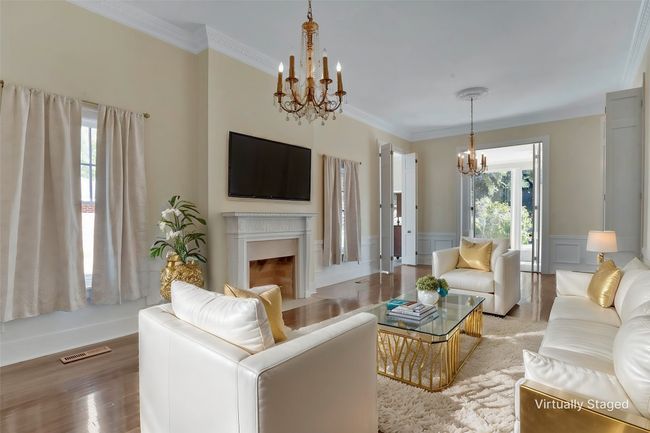 Living room with a chandelier, a fireplace, wood finished floors, a wainscoted wall, and crown molding | Image 12