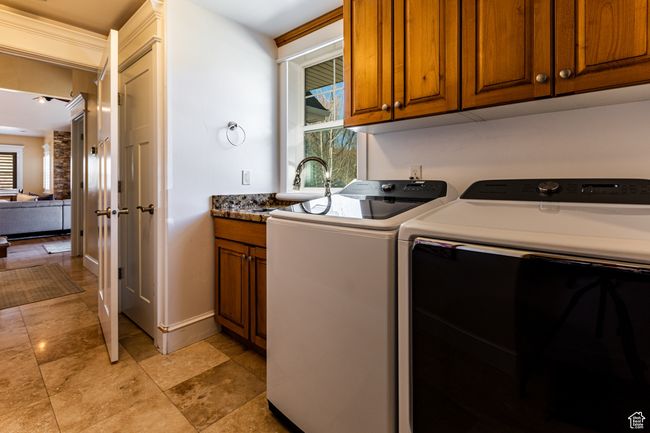 Washroom with a wealth of natural light, washer and clothes dryer, cabinet space, and a sink | Image 29