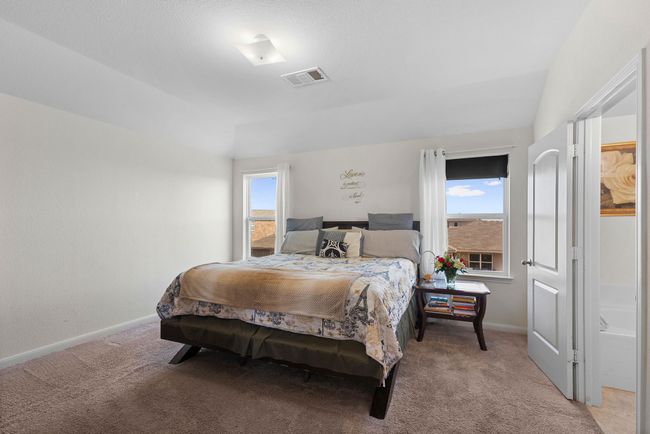 Bedroom with vaulted ceiling, baseboards, visible vents, and light colored carpet | Image 25