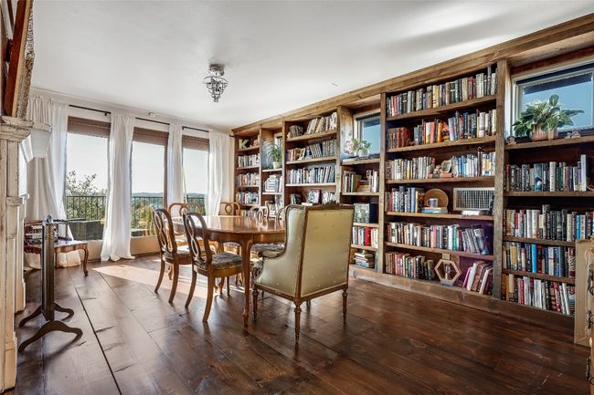Sitting room with wood finished floors and wall of books | Image 15
