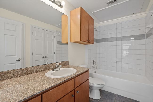 Bathroom featuring vanity, washtub / shower combination, and dark tile patterned flooring | Image 21