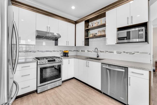 Kitchen with appliances with stainless steel finishes, extractor fan, backsplash, ornamental molding, and white cabinets | Image 7