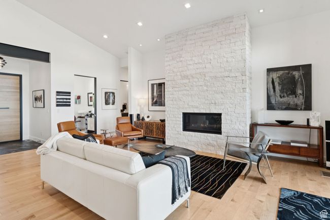 Living room with wood finished floors, high vaulted ceiling, a stone fireplace, and recessed lighting | Image 14