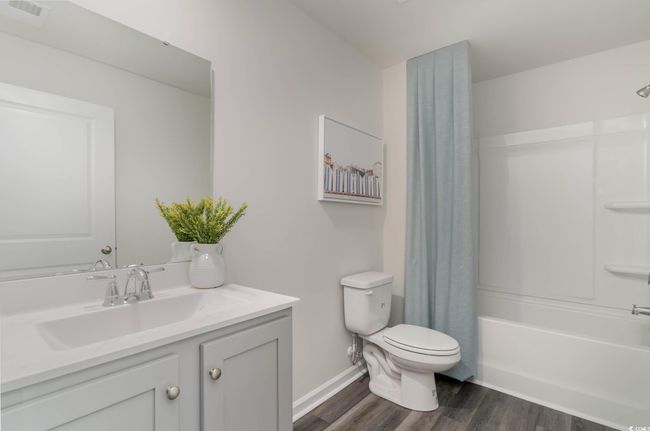 Full bathroom with toilet, wood finished floors, vanity, shower / tub combo with curtain, and baseboards | Image 27