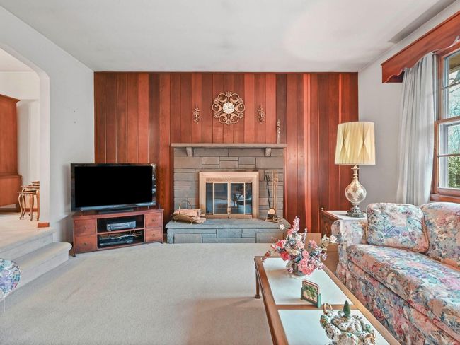 Carpeted living room with a stone fireplace and wood walls | Image 10