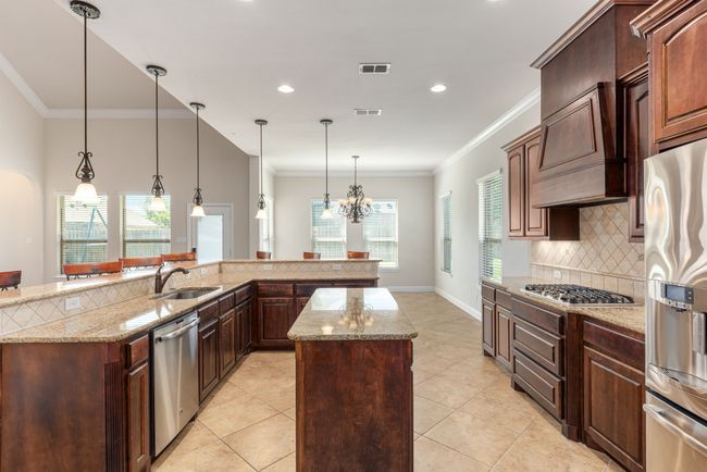 Kitchen with a center island, tasteful backsplash, an inviting chandelier, appliances with stainless steel finishes, and visible vents | Image 21