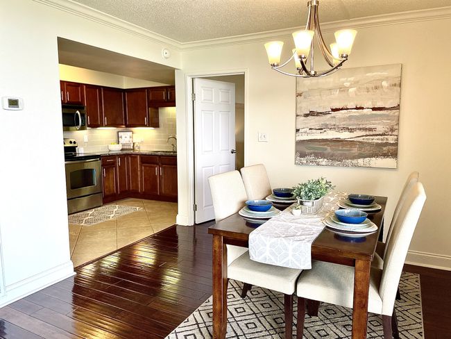 Discover the ideal dining room within this residence, complete with modernized chandelier, elegant crown molding, beautiful hardwood floors, and a soothing neutral color palette. | Image 5