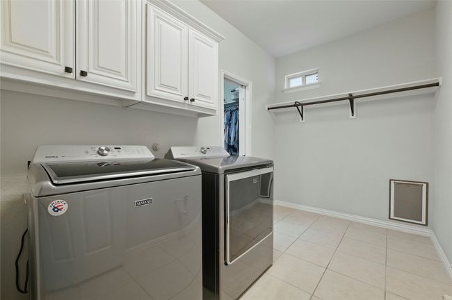 Washroom featuring cabinet space, washing machine and clothes dryer, and light tile patterned floors | Image 26