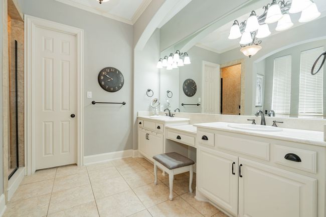 Bathroom with tile patterned floors, ornamental molding, a sink, a chandelier, and tiled shower | Image 20