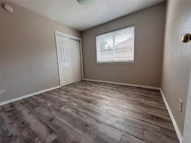 Unfurnished bedroom featuring wood finished floors, a textured ceiling, and a closet | Image 15