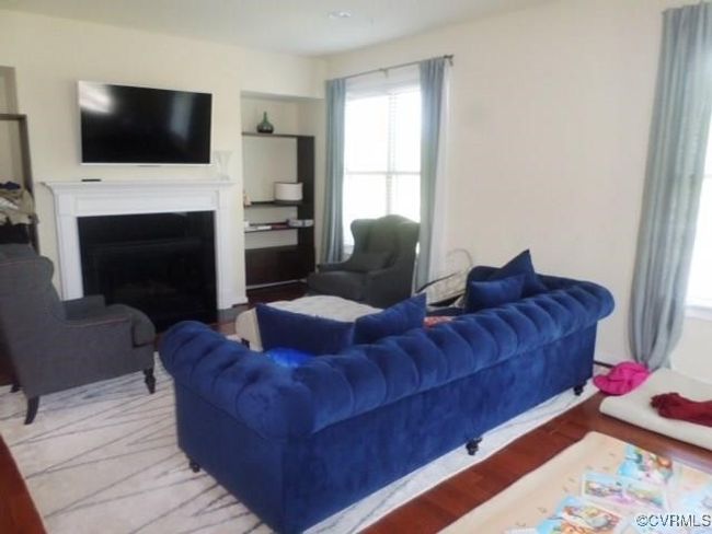 Living room with built in shelves, wood finished floors, and a fireplace | Image 7