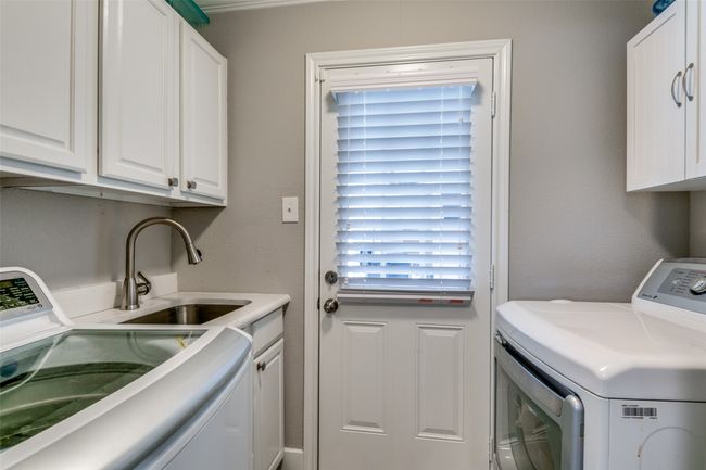 Full sized laundry area with a sink. Door is an exit to patio and pool area. | Image 14
