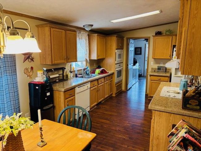 Kitchen with dark wood-type flooring, white appliances, light countertops, and ornamental molding | Image 19