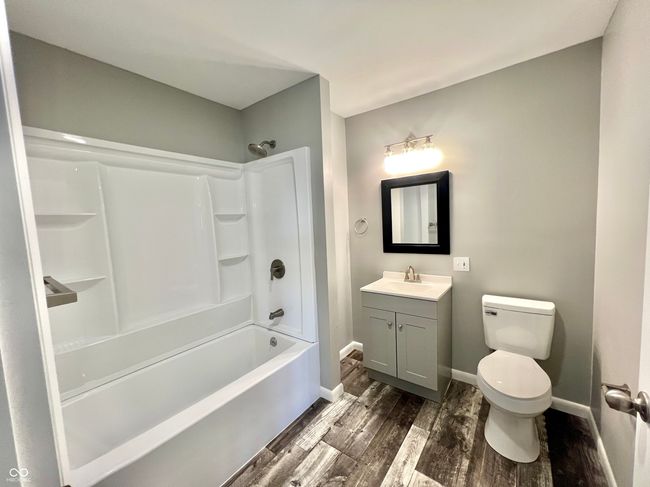 full bath featuring baseboards, toilet, shower combination, vanity, and wood finished floors | Image 13