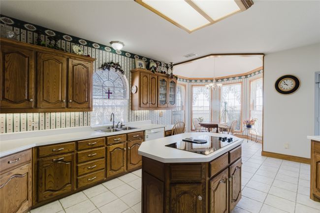 Kitchen with a kitchen island, an inviting chandelier, sink, black electric stovetop, and light tile patterned flooring | Image 16