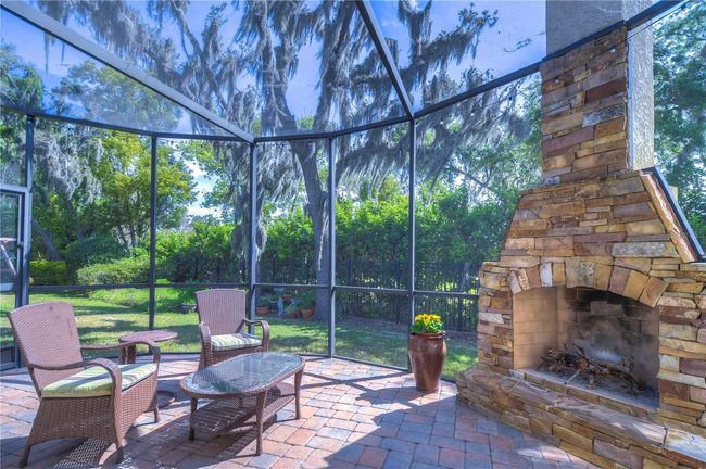 Step into your own backyard oasis featuring a beautifully screened-in patio with a rustic stone fireplace. | Image 33