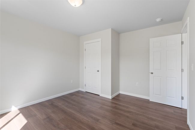 Unfurnished bedroom with dark wood-style flooring and baseboards | Image 52