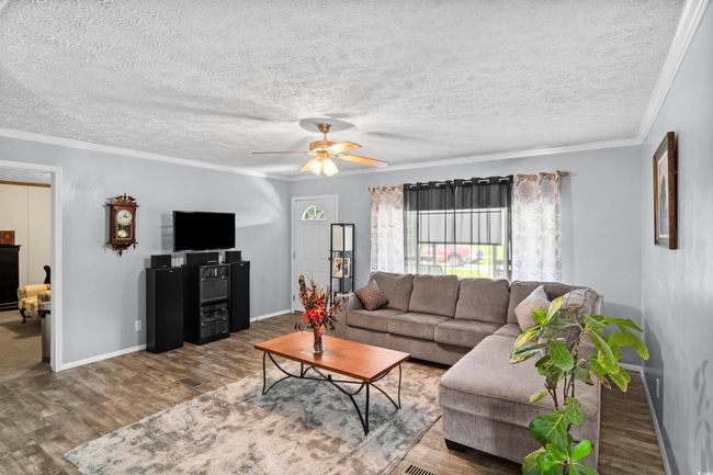 Living area featuring wood finished floors, a ceiling fan, ornamental molding, and a textured ceiling | Image 30