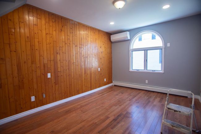 Unfurnished room featuring an AC wall unit, wood walls, and a baseboard radiator | Image 17