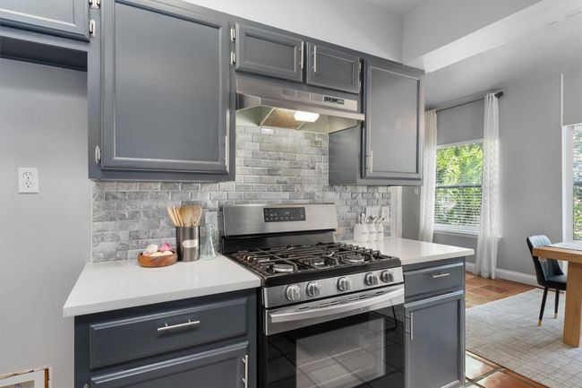 Kitchen featuring stainless steel range with gas stovetop, under cabinet range hood, tasteful backsplash, and light countertops | Image 13