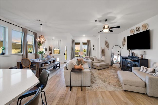 This spacious living area features an open floor plan with abundant natural light, modern furnishings, and stylish decor. It includes a cozy seating area, a large TV, and a dining space, creating a comfortable and inviting atmosphere for entertaining or relaxing. | Image 28