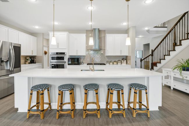 The kitchen is open with a large sit up breakfast bar with pendant lighting. | Image 12