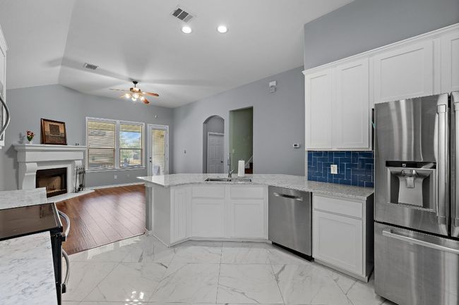 Kitchen featuring stainless steel appliances, a sink, open floor plan, and a peninsula | Image 10