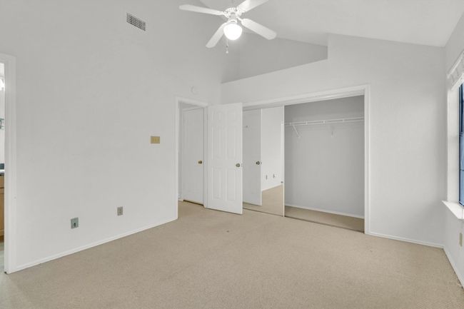 Unfurnished bedroom featuring carpet floors, baseboards, lofted ceiling, and visible vents | Image 18