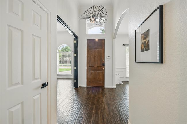 Foyer entrance featuring arched walkways, dark wood-type flooring, a textured wall, and a towering ceiling | Image 6