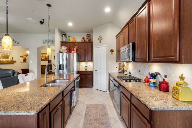 Kitchen with stainless steel appliances, a sink, tasteful backsplash, light tile patterned flooring, and arched walkways | Image 11