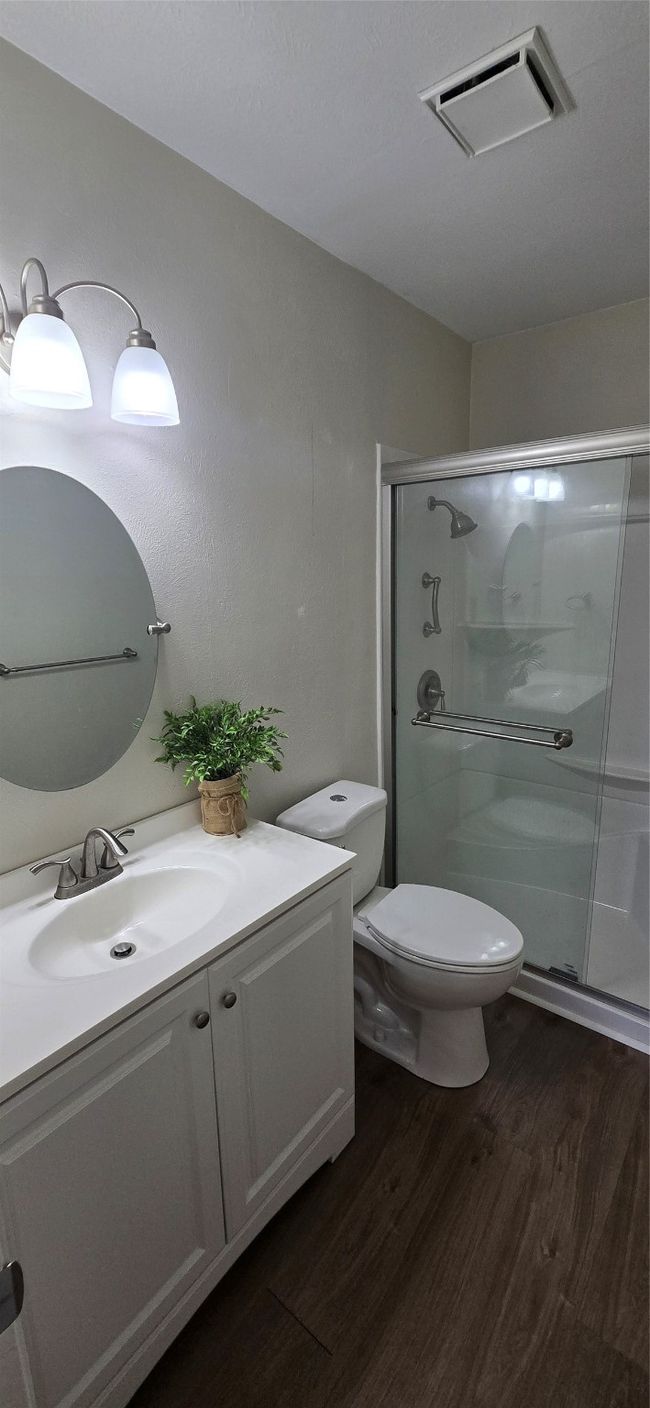 Full bathroom featuring wood finished floors, vanity, and a shower stall | Image 5