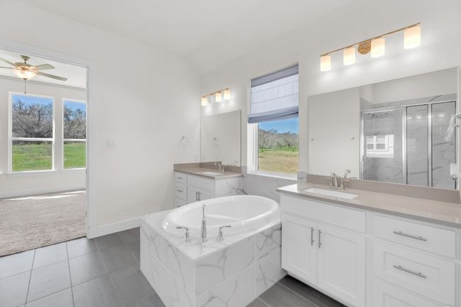 Full bathroom featuring a stall shower, two vanities, a sink, and tile patterned flooring | Image 24