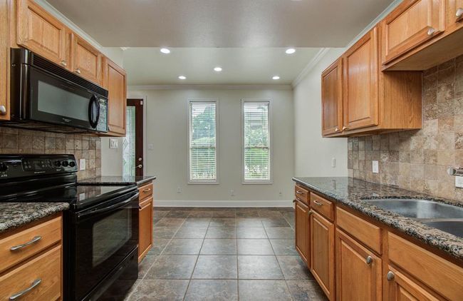 Spacious kitchen featuring sleek granite countertops, modern appliances, and warm wooden cabinetry, perfect for culinary enthusiasts. | Image 9