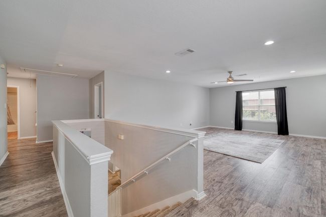 Empty room featuring attic access, wood finished floors, a ceiling fan, and recessed lighting | Image 17
