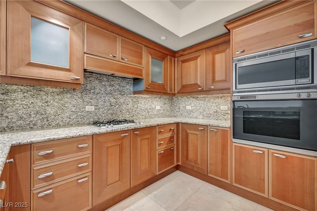 Kitchen featuring stainless steel microwave, backsplash, light stone countertops, and oven | Image 26