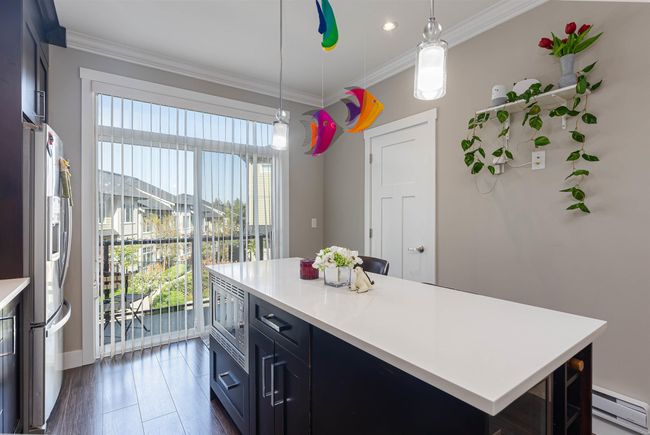 Kitchen with a baseboard heating unit, light countertops, crown molding, appliances with stainless steel finishes, and decorative light fixtures | Image 18